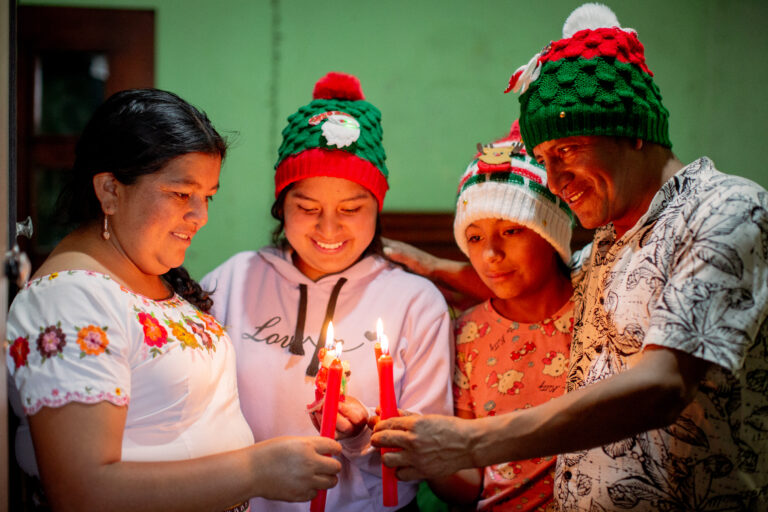 Familia ecuatoriana encendiendo velas de Adviento, celebrando el amor y la unidad en Cristo durante la Navidad.